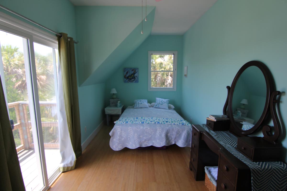 Bright aqua bedroom with balcony access at Goat Island Resort Rental House